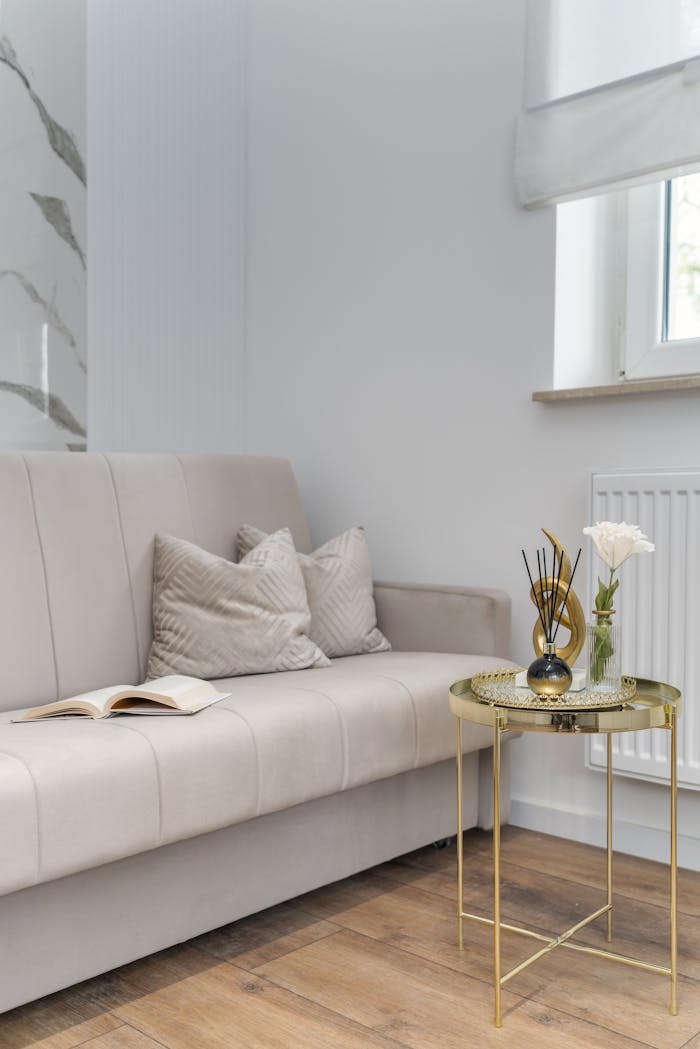 Stylish interior with beige sofa, pillows, and a gold coffee table beside a window.